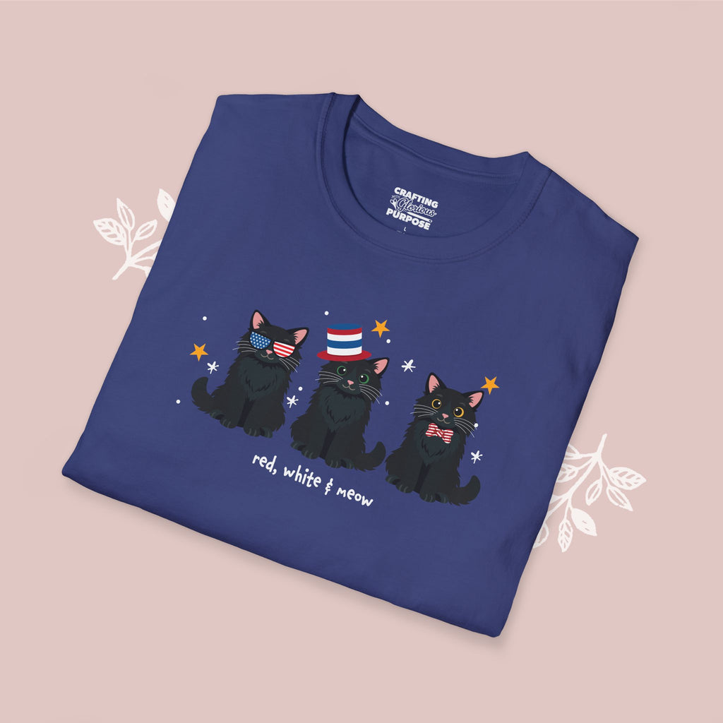 Folded blue t-shirt with black cats and text on a pink background