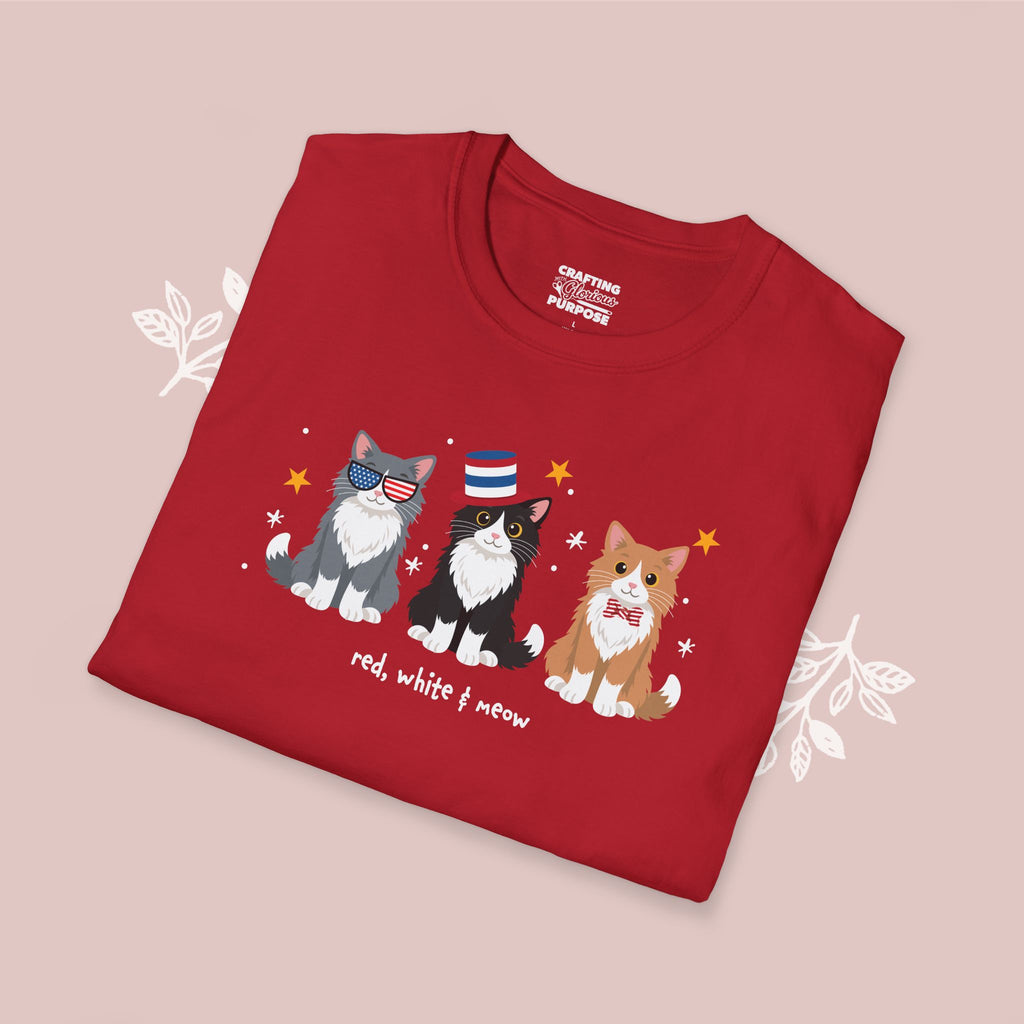 Folded red t-shirt with cat illustrations and text on a pink background