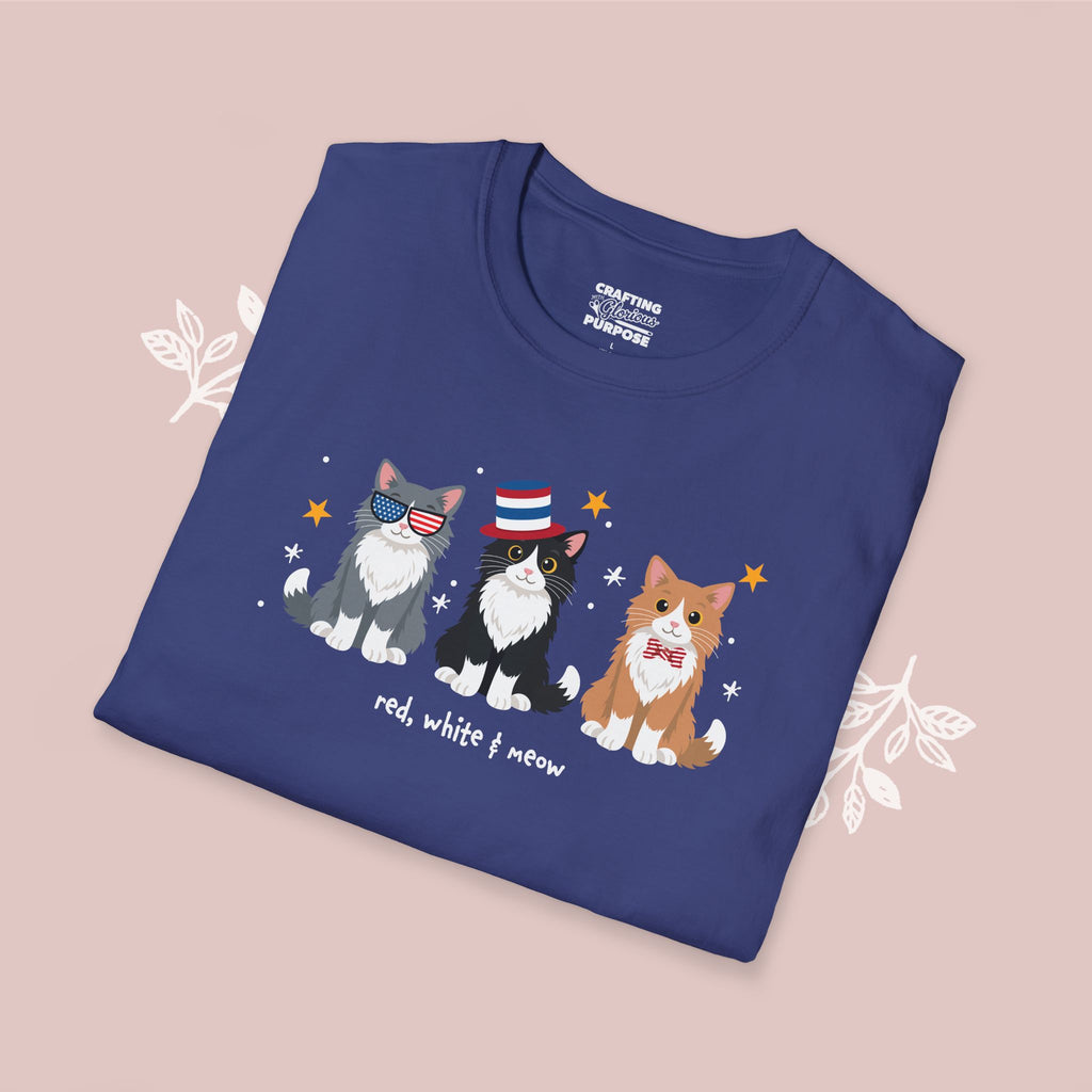 Folded blue t-shirt with cats wearing American flag sunglasses and a bow tie on a pink background