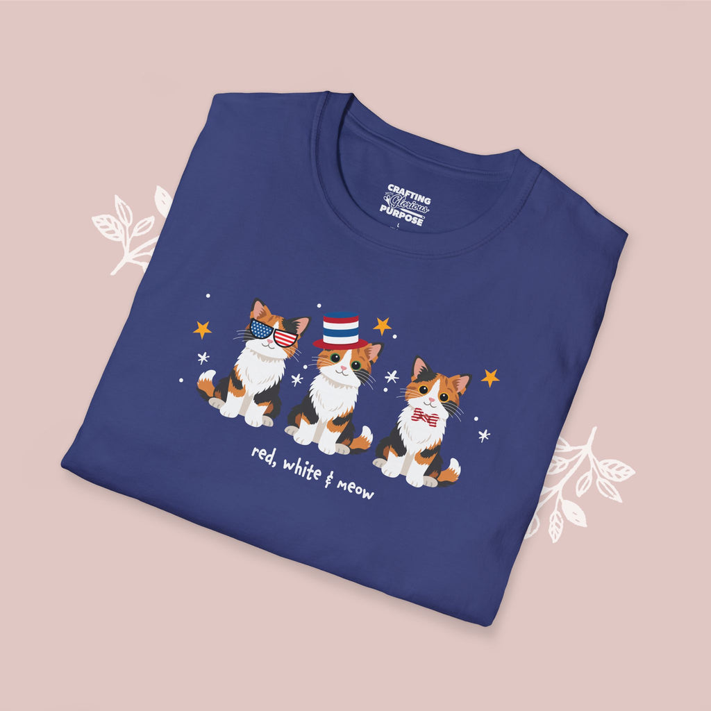 Folded blue t-shirt with cat illustrations and text on a pink background