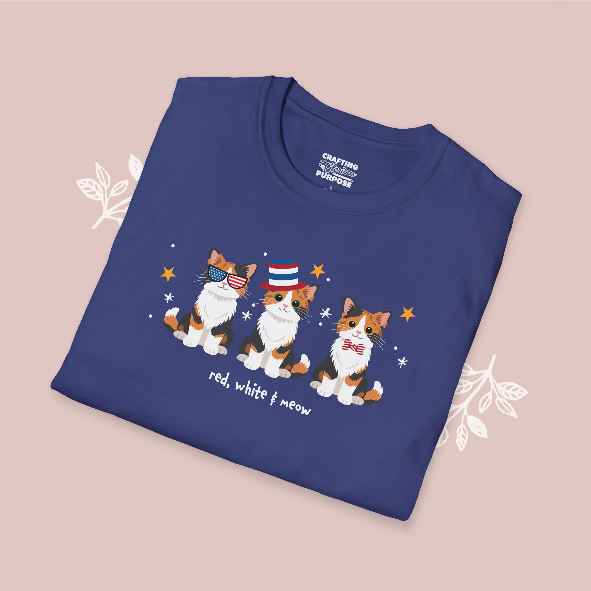 Folded blue t-shirt with cat illustrations and text on a pink background