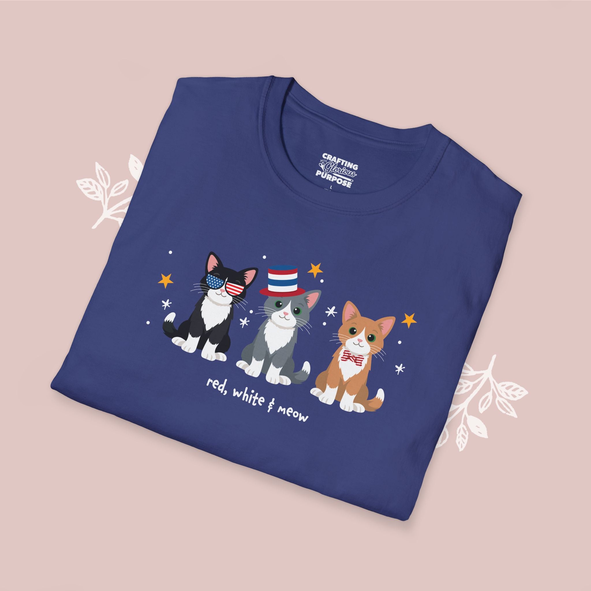 Folded blue t-shirt with cat illustrations and text on a pink background