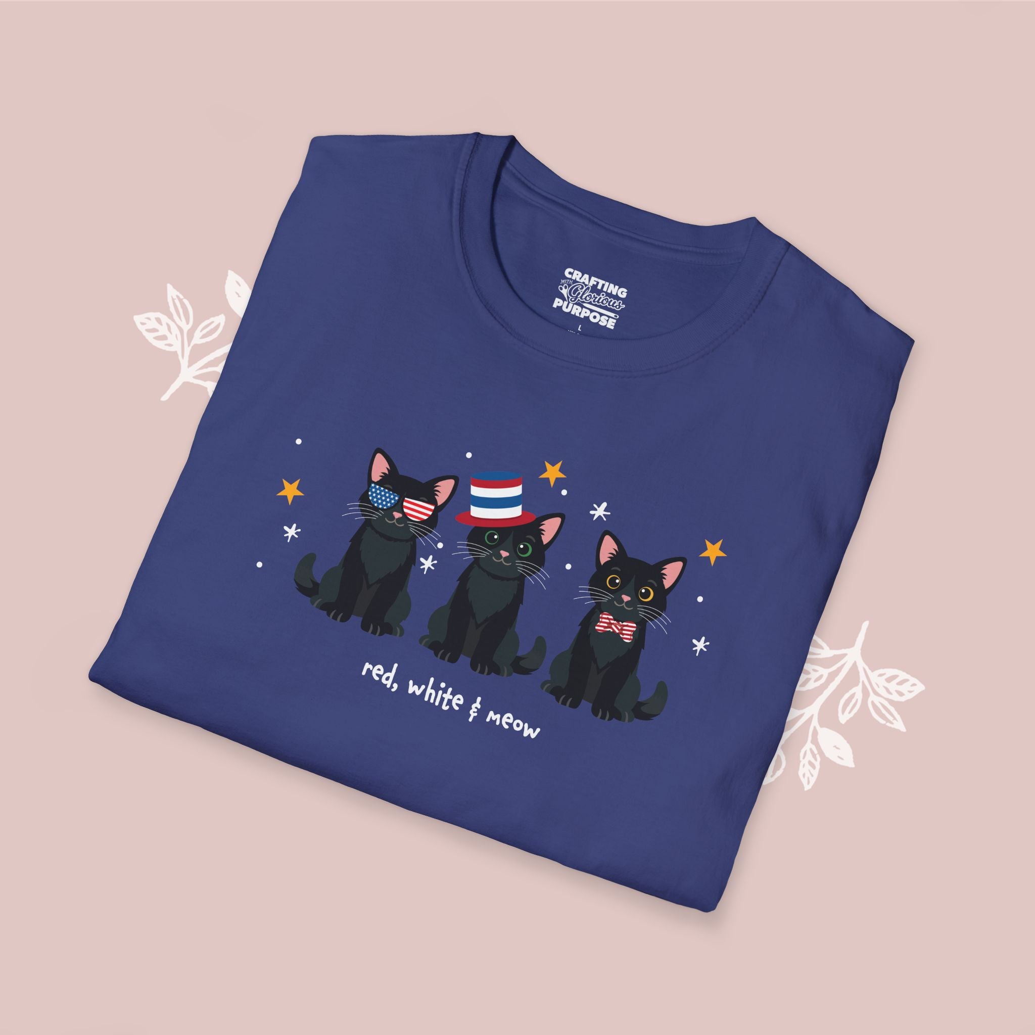 Folded blue t-shirt with black cats wearing American flag hats on a pink background