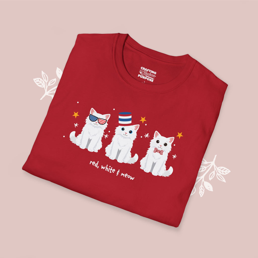 Folded red t-shirt with cat illustrations and text on a pink background