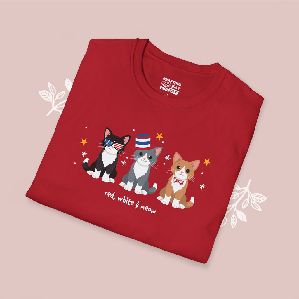 Folded red t-shirt with cat illustrations and text on a pink background