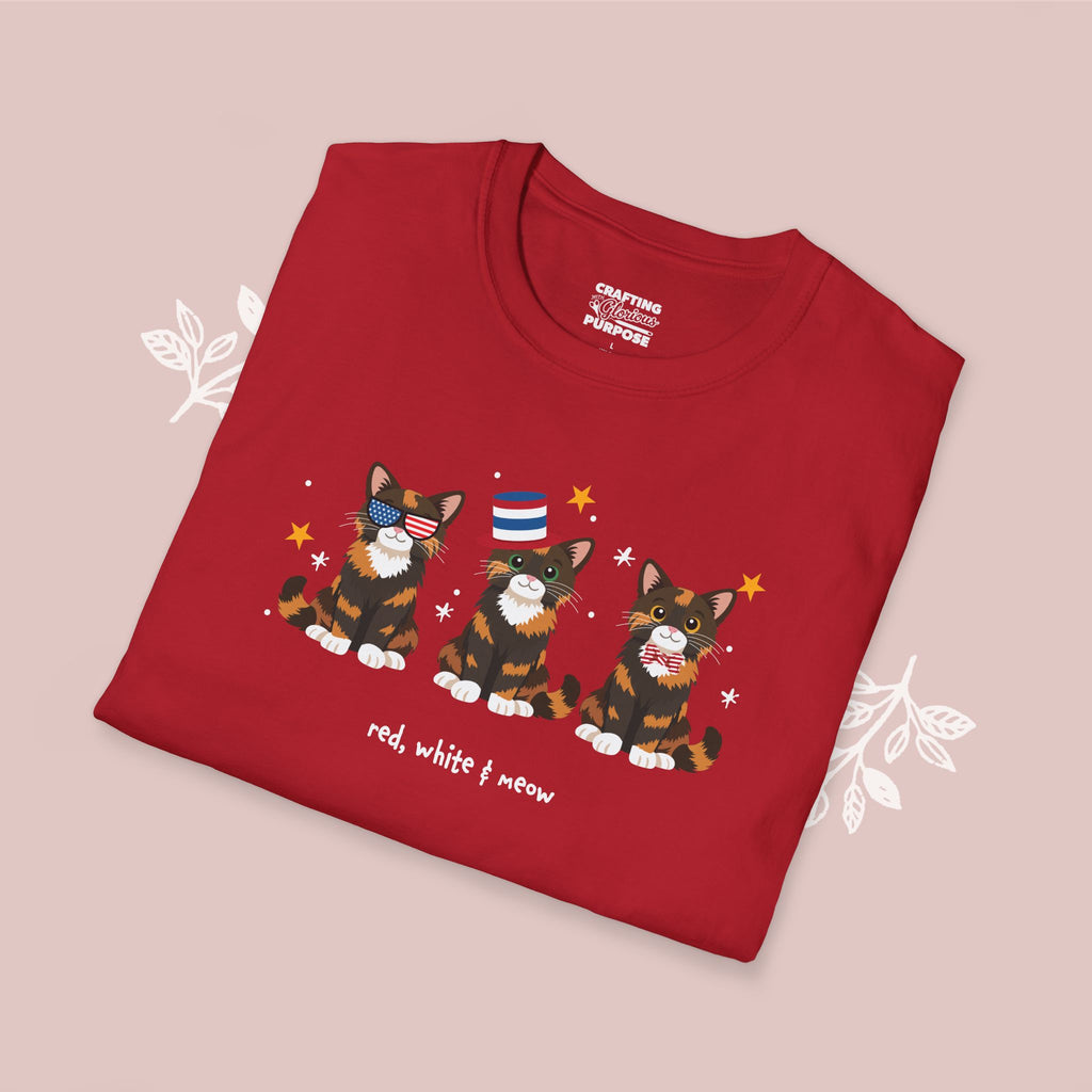 Folded red t-shirt with cat illustrations and text on a pink background