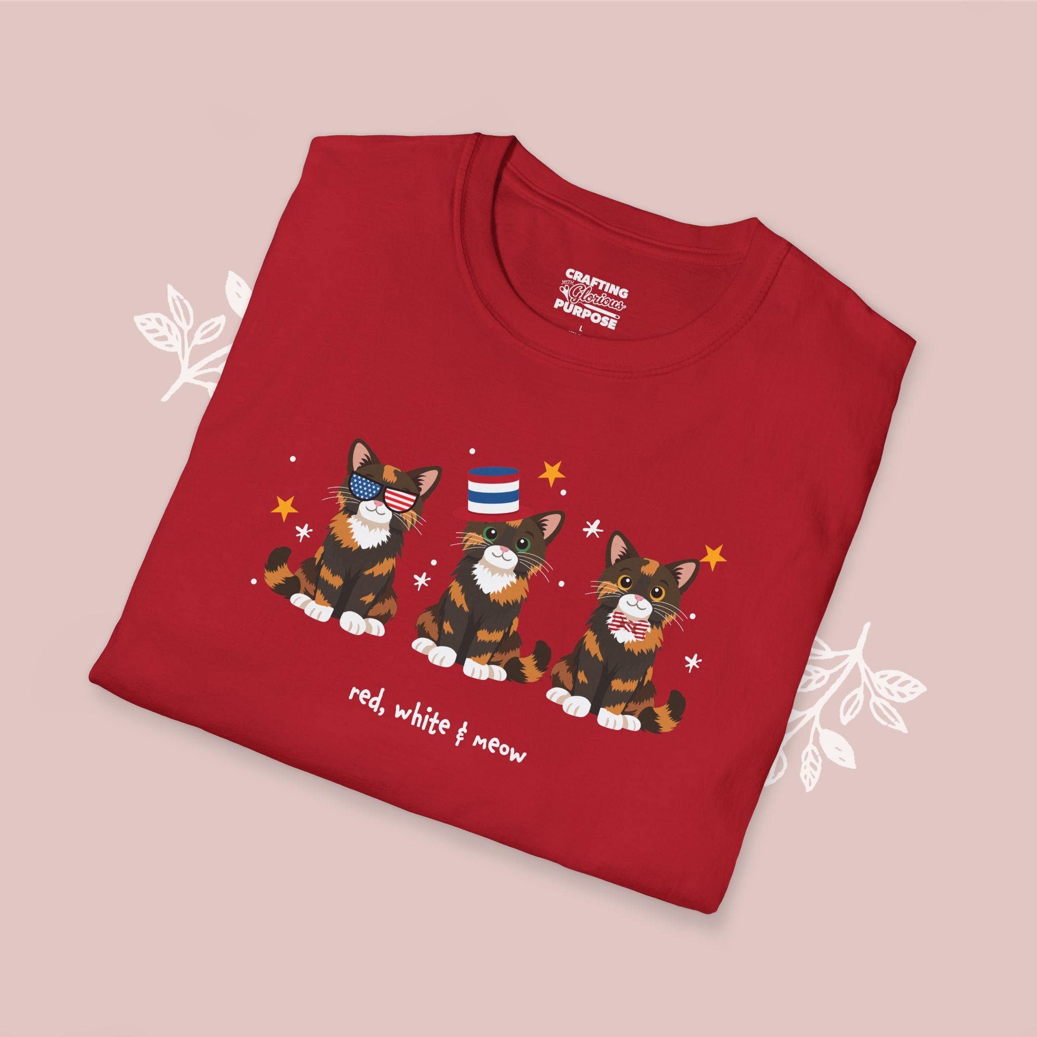 Folded red t-shirt with cat illustrations and text on a pink background