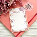 Notepad with 'brain dump' design on a pink surface with flowers