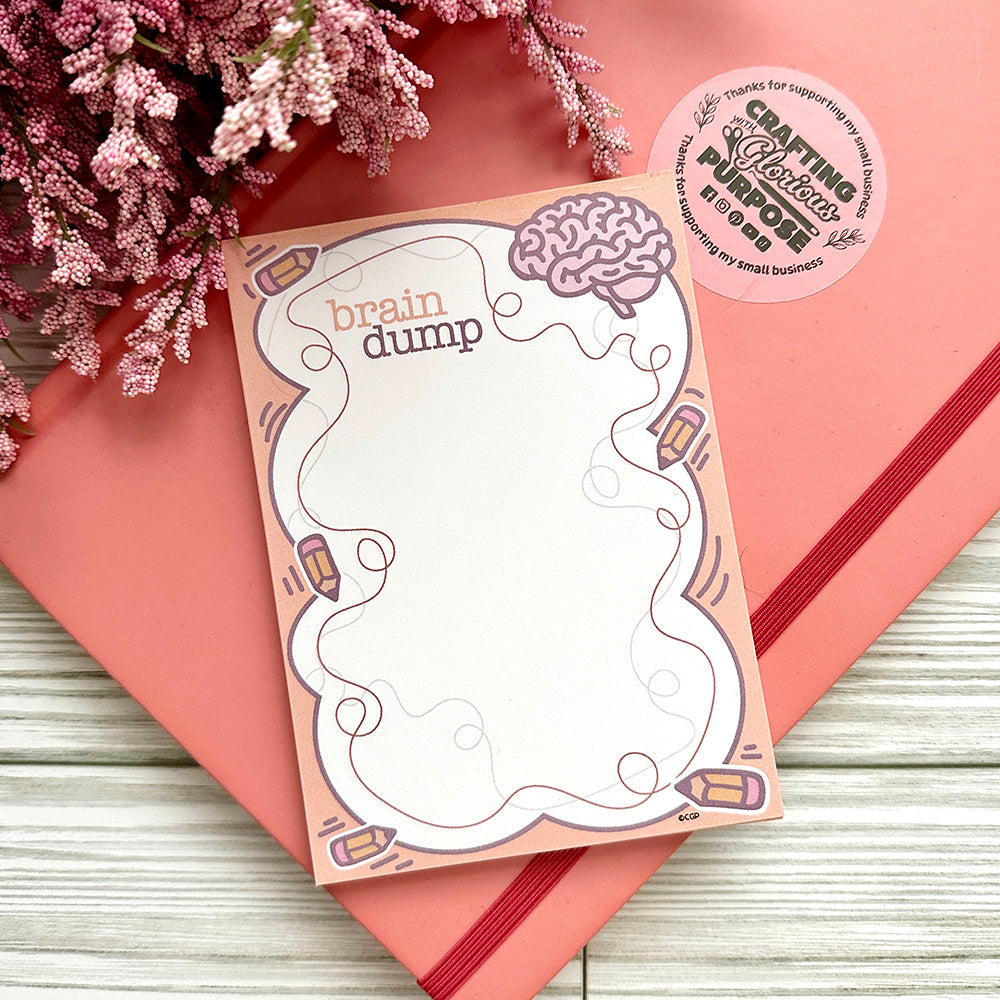 Notepad with 'brain dump' design on a pink surface with flowers