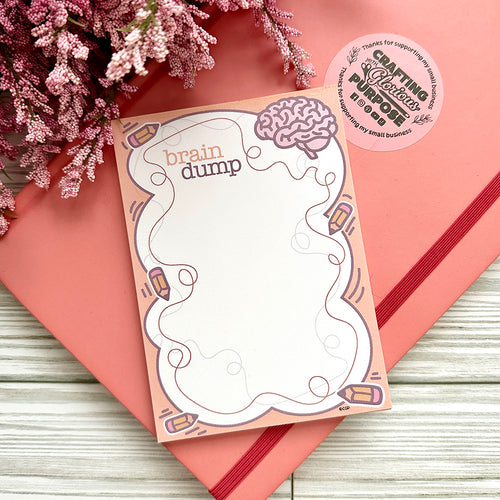 Notepad with 'brain dump' design on a pink surface with flowers
