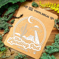 Vinyl decal packaging with nature-themed design on a wooden surface with greenery.