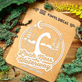 Vinyl decal of Loch Ness Waterway on a brown card with greenery around