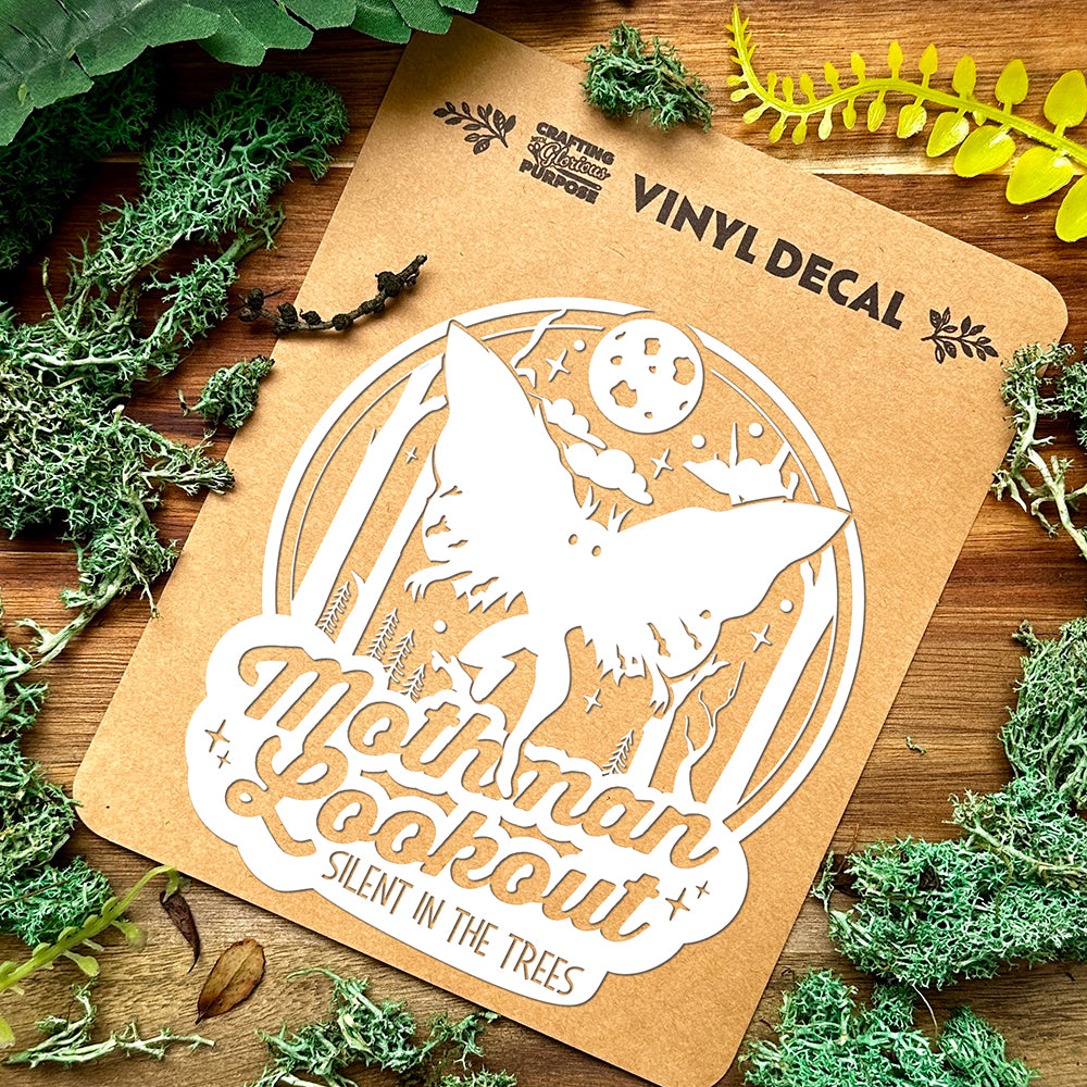 Vinyl decal of a mothman on a brown card with nature-themed elements.