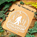 Vinyl decal for Sasquatch Mountain with nature-themed design on a wooden surface.