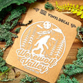 Vinyl decal of a werewolf with 'Werewolf Valley' text on a brown card, surrounded by green foliage.
