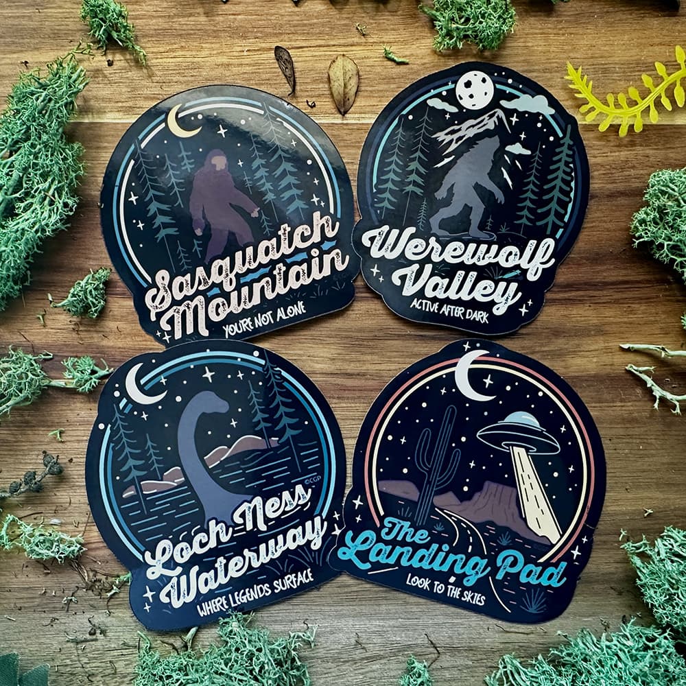 Four themed stickers on a wooden background with foliage.