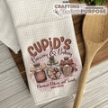 Kitchen towel with 'Cupid's Brewery & Bakery' design on a wooden surface with a wooden spoon.