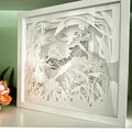 Decorative wall art with floral and dragonfly design in a white frame.
