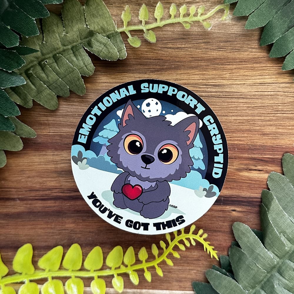 Circular sticker with a cartoon character holding a heart, surrounded by green leaves on a wooden surface.