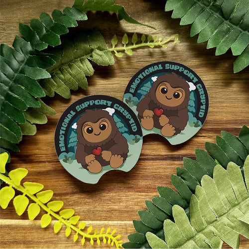 Two stickers with cartoon characters and text on a wooden surface with leaves around.