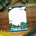Notebook with a cartoon dinosaur design on a wooden surface with leaves.