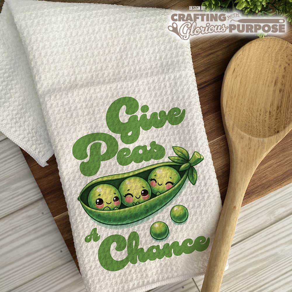 Kitchen towel with peas in a pod design and wooden spoon on a wooden surface