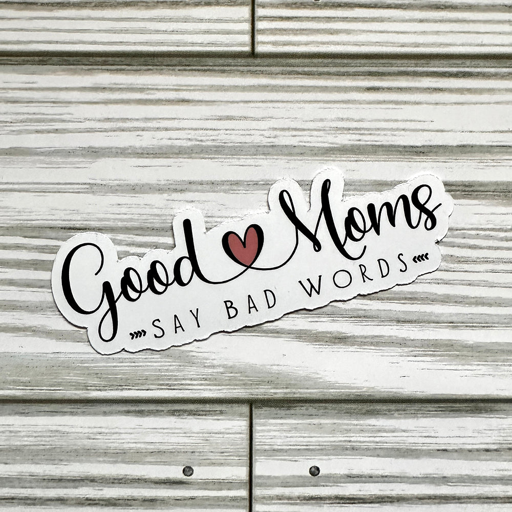 Sticker with 'Good moms say bad words' text on a wooden surface