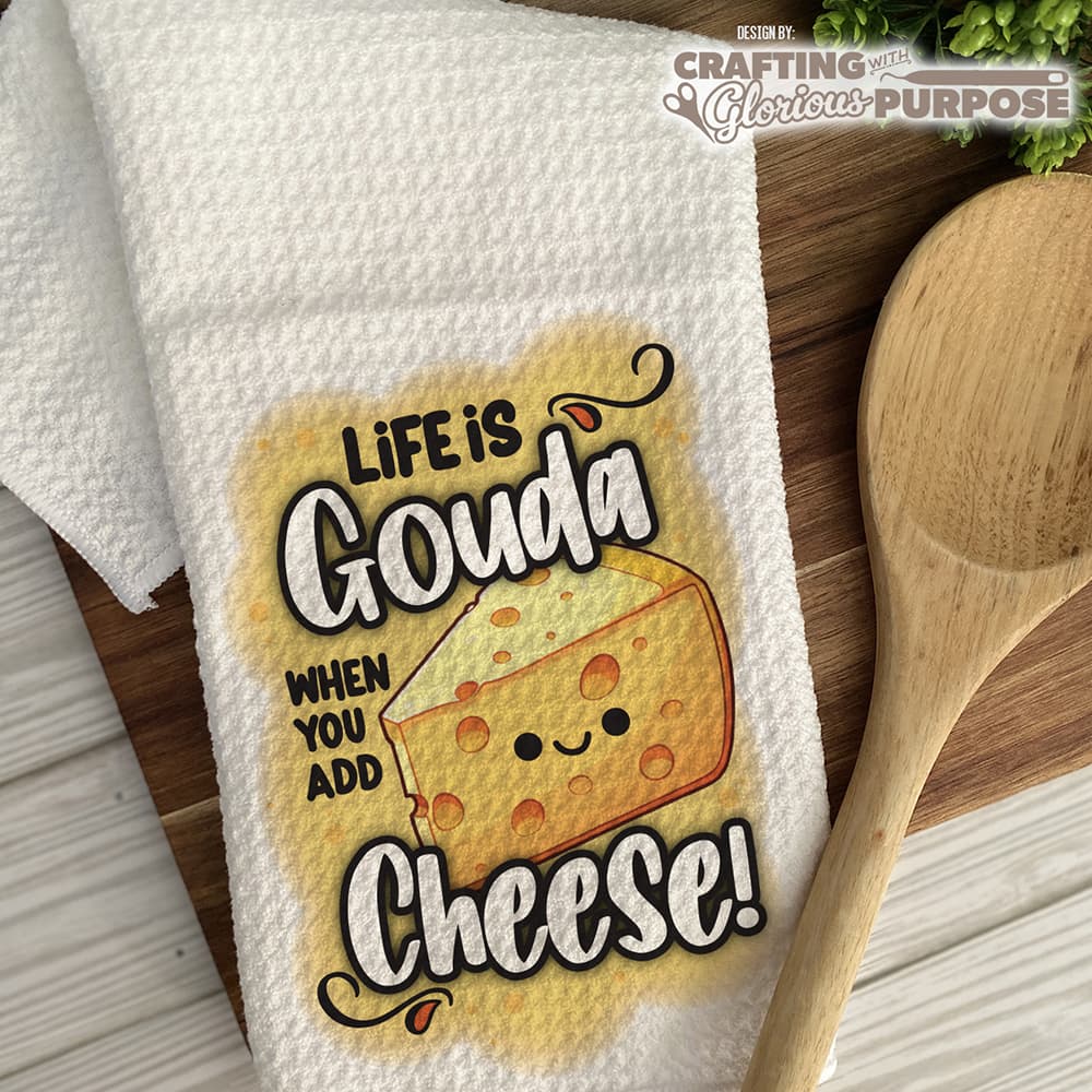 Dish towel with cheese-themed design and wooden spoon on a wooden surface