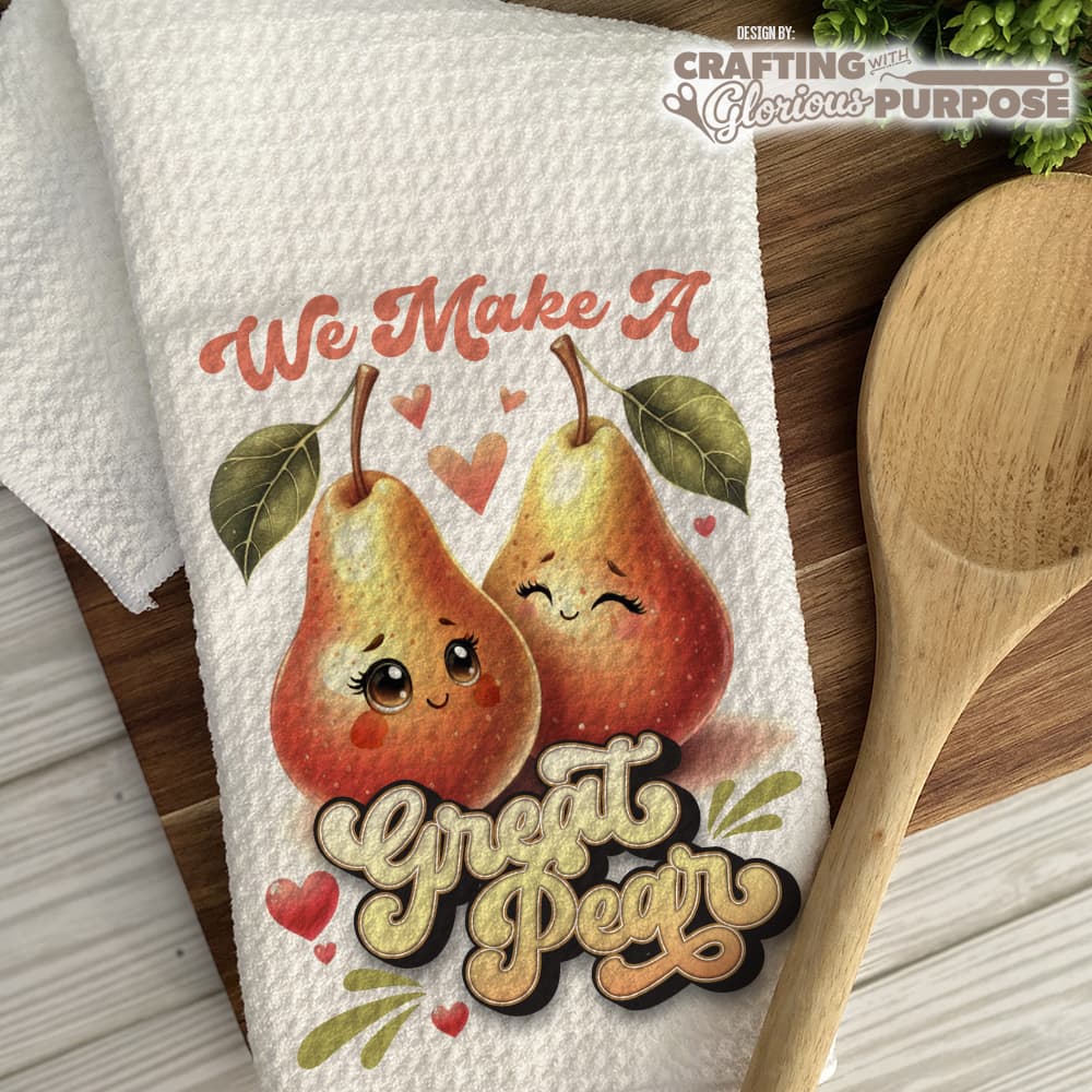 Towel with cartoon pears and text 'We Make A Great Pear' on a wooden surface.