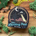 Sticker with UFO design on a wooden surface with greenery