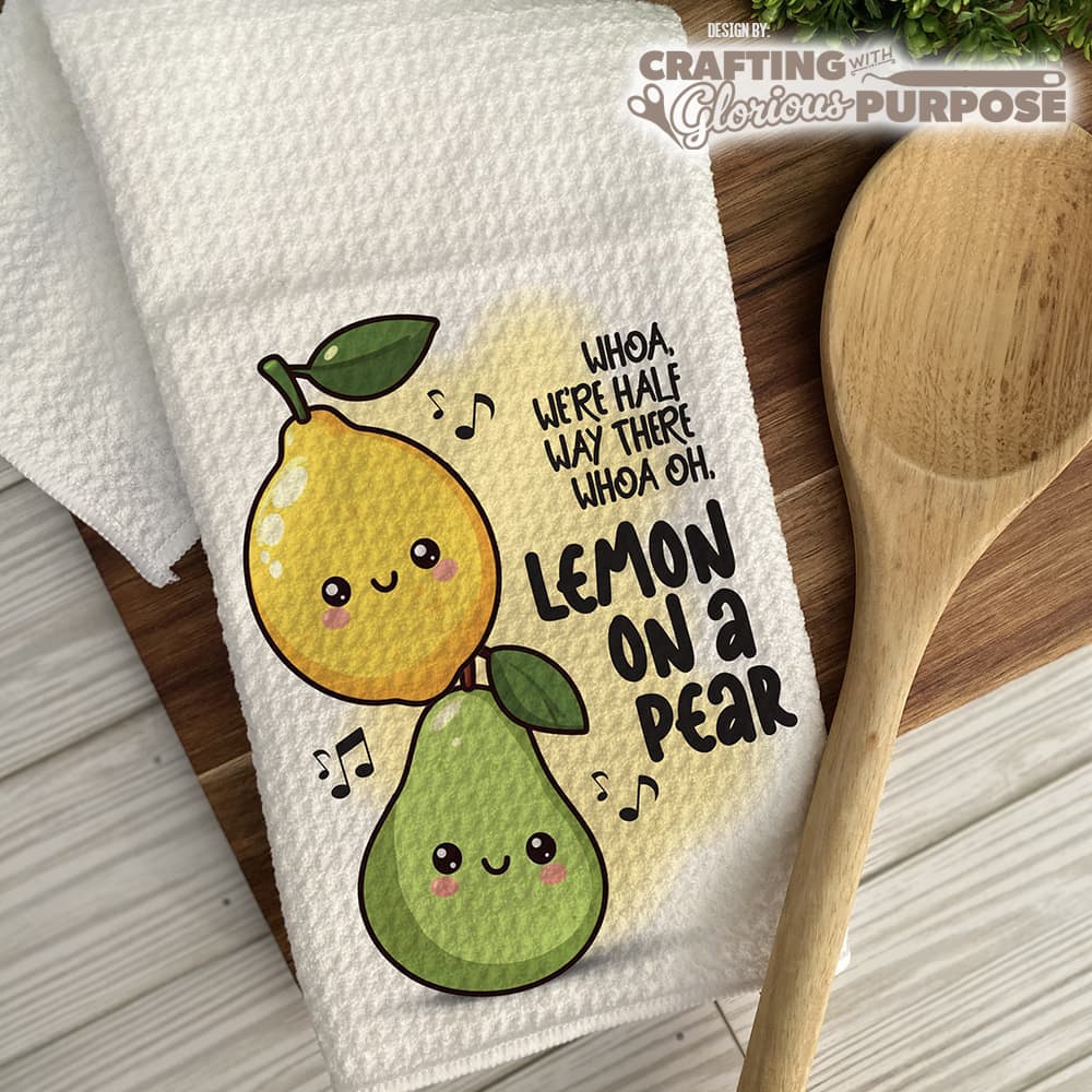 Kitchen towel with cartoon lemons and pears and text, next to a wooden spoon on a wooden surface.