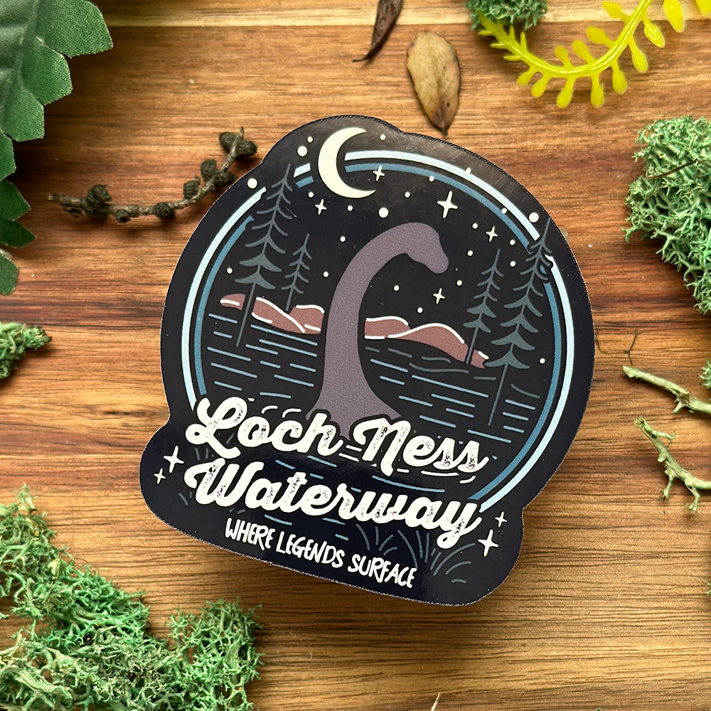 Sticker with Loch Ness Monster design on a wooden surface with greenery