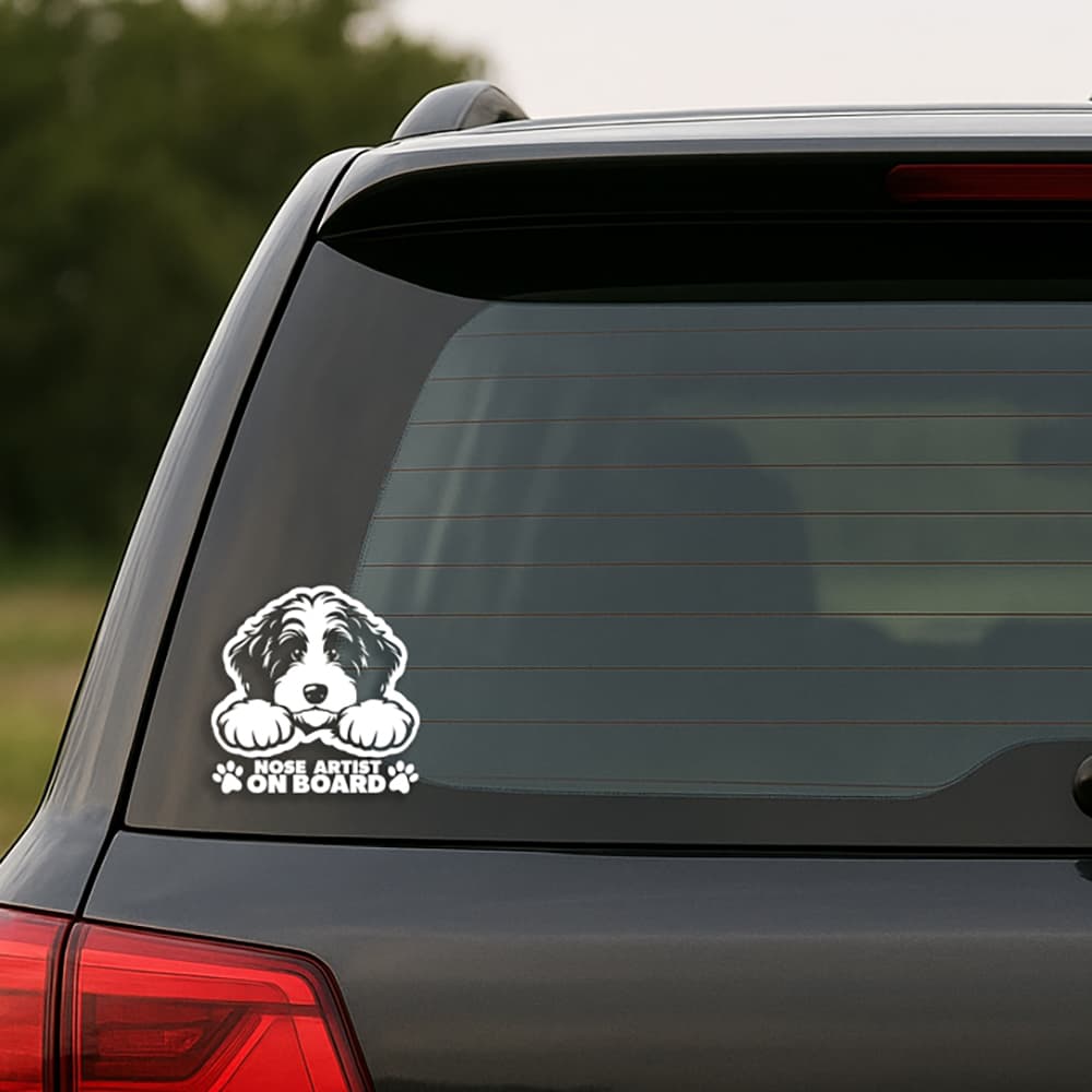 Car window with a dog sticker and 'Nose Artist on Board' text