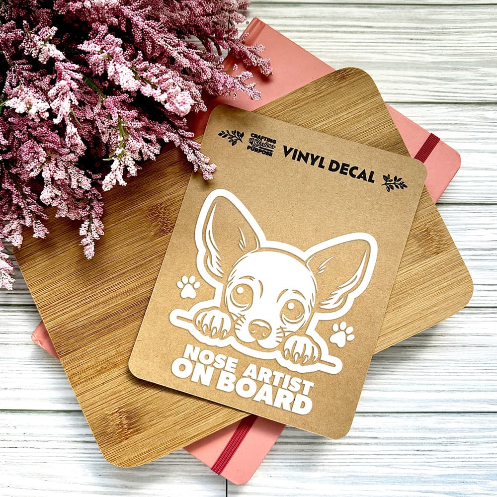 Vinyl decal with a dog illustration and text on a wooden surface with pink flowers.