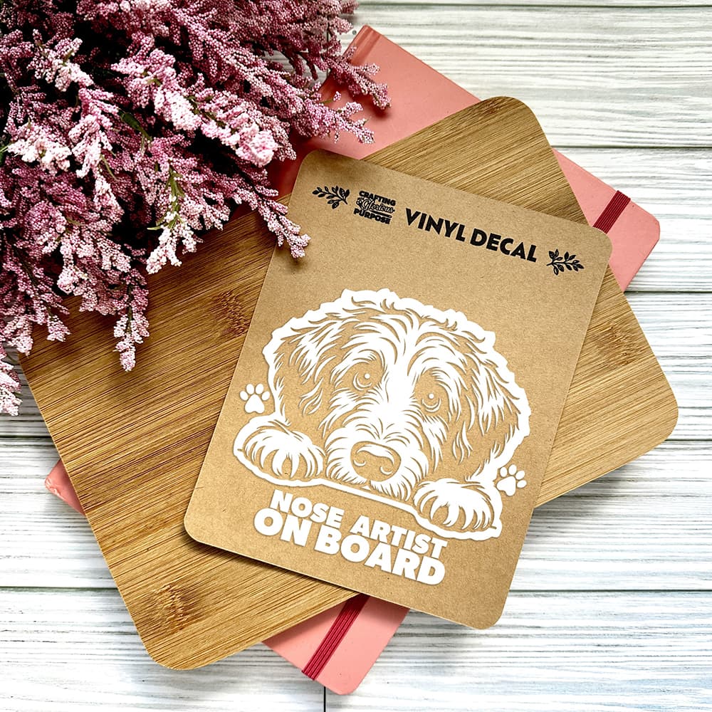 Vinyl decal with a dog illustration and text on a wooden surface with pink flowers.