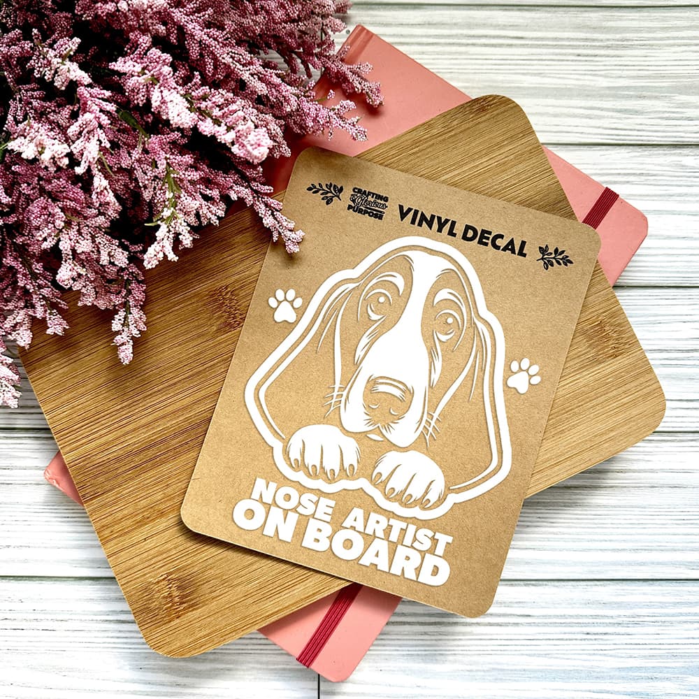 Vinyl decal with a dog illustration and text on a wooden surface with pink flowers.