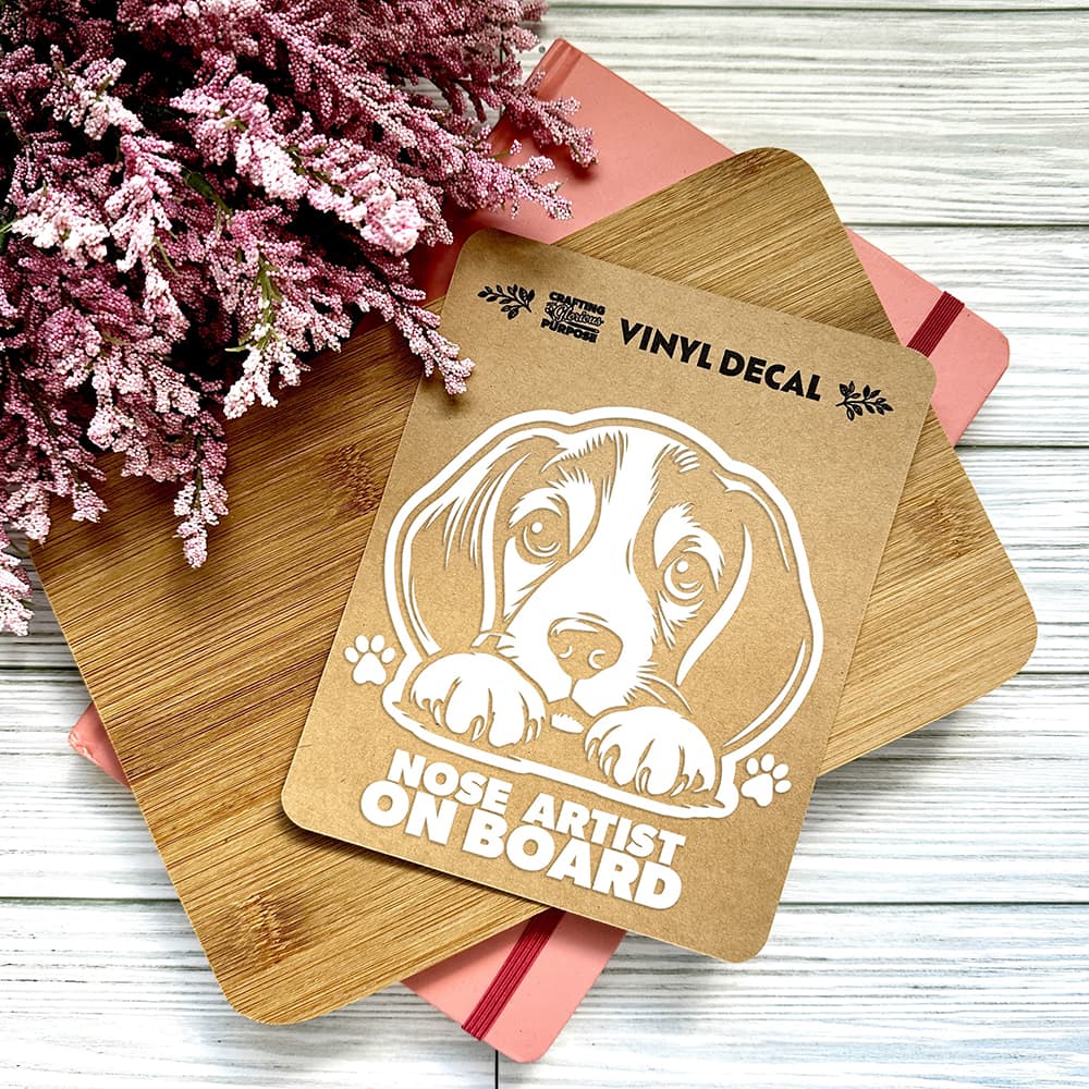 Vinyl decal with a dog illustration and text on a wooden surface with pink flowers.