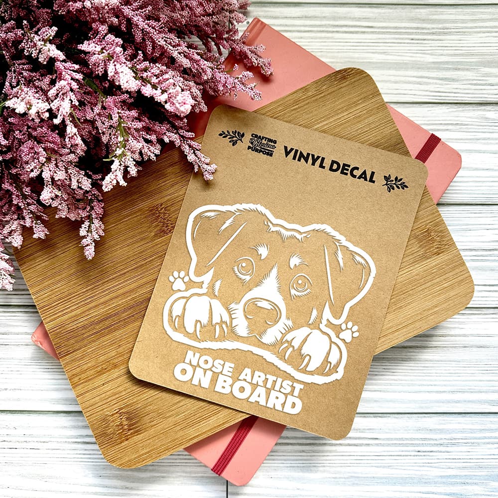Vinyl decal with a dog illustration and text on a wooden surface with pink flowers.