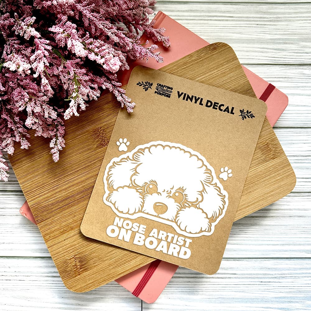 Vinyl decal with a dog illustration and text on a wooden surface with pink flowers.