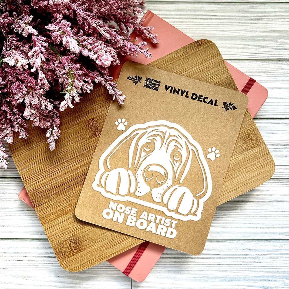 Vinyl decal with a dog illustration and text on a wooden surface with pink flowers.