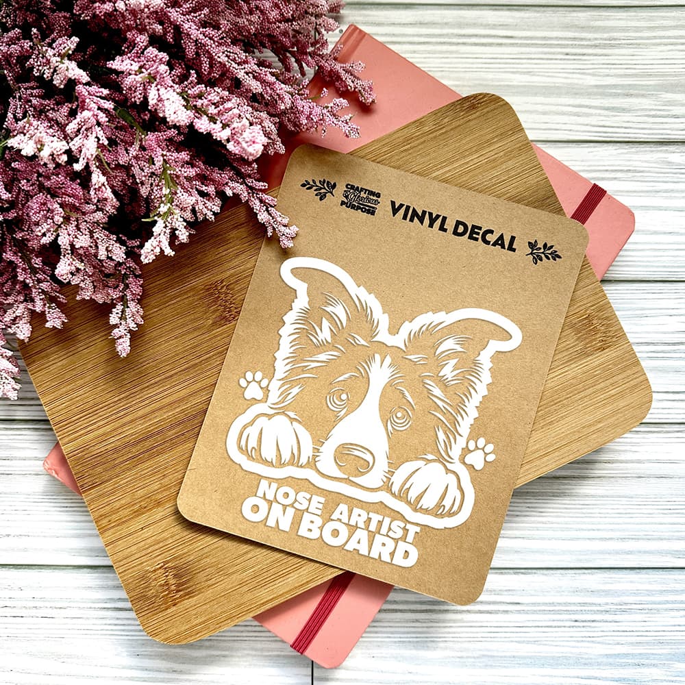 Vinyl decal with a dog illustration and text on a wooden surface with pink flowers.