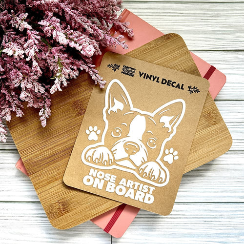 Vinyl decal with a dog illustration and text on a wooden surface with pink flowers.
