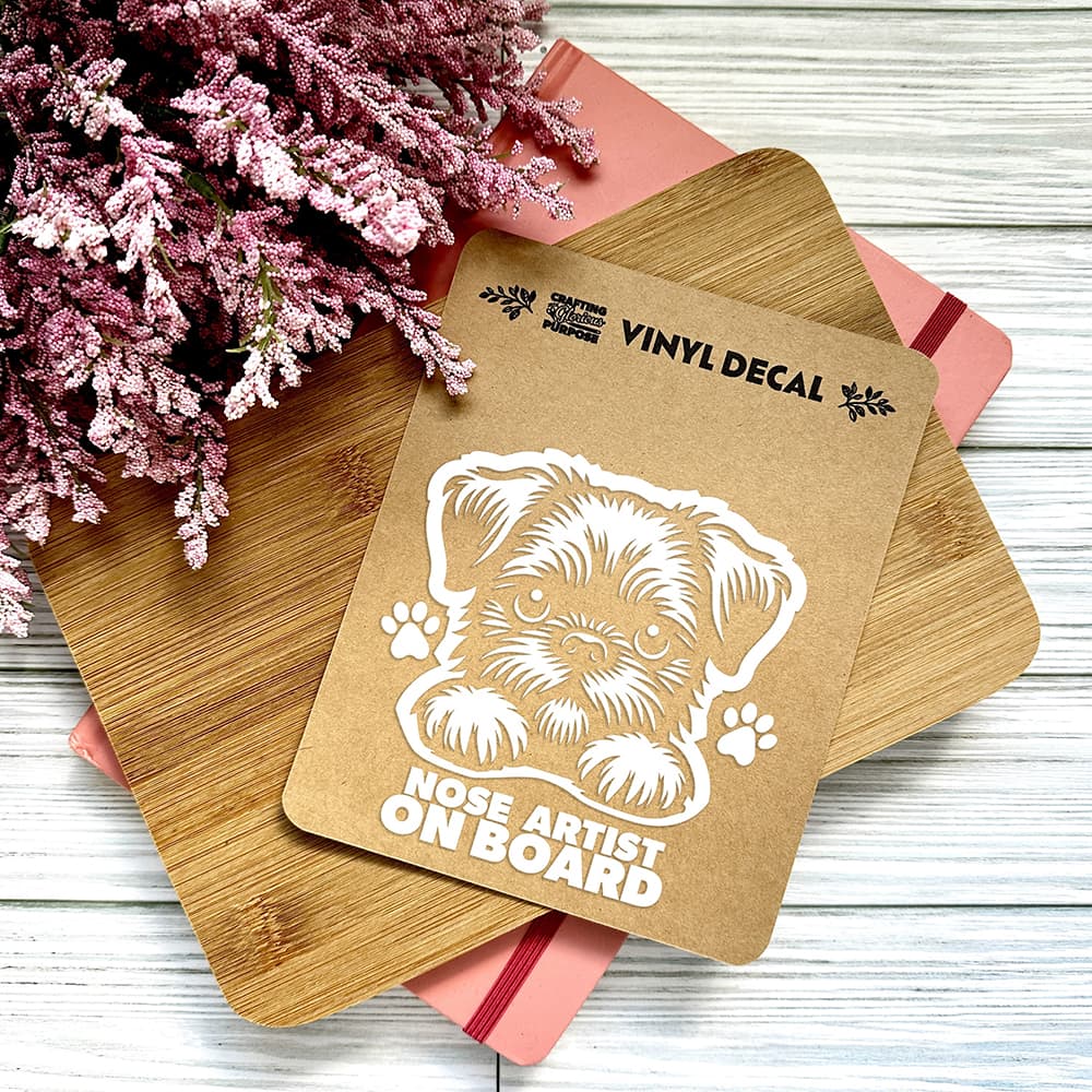 Vinyl decal with a dog illustration and text on a wooden surface with pink flowers.