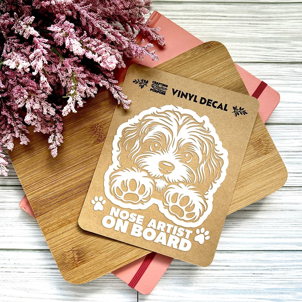 Vinyl decal with a dog illustration and text on a wooden surface with pink flowers.