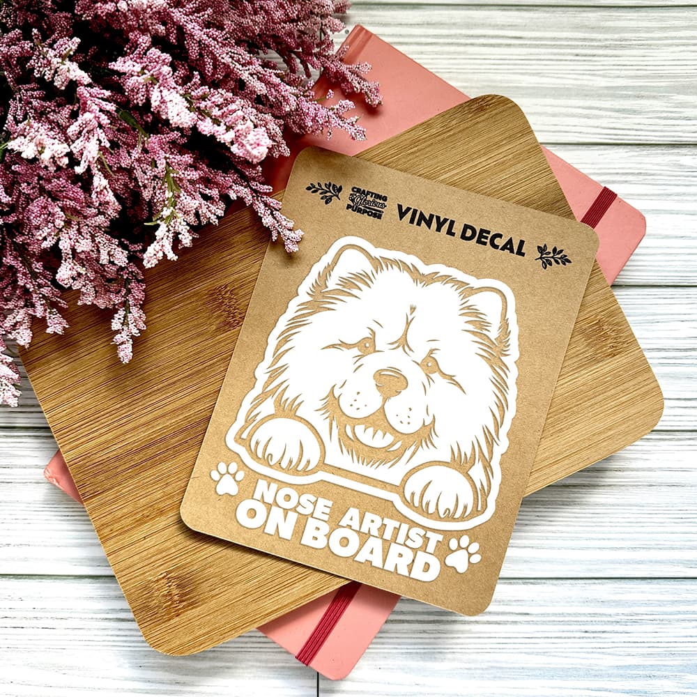 Vinyl decal with a dog illustration and text on a wooden surface with pink flowers.