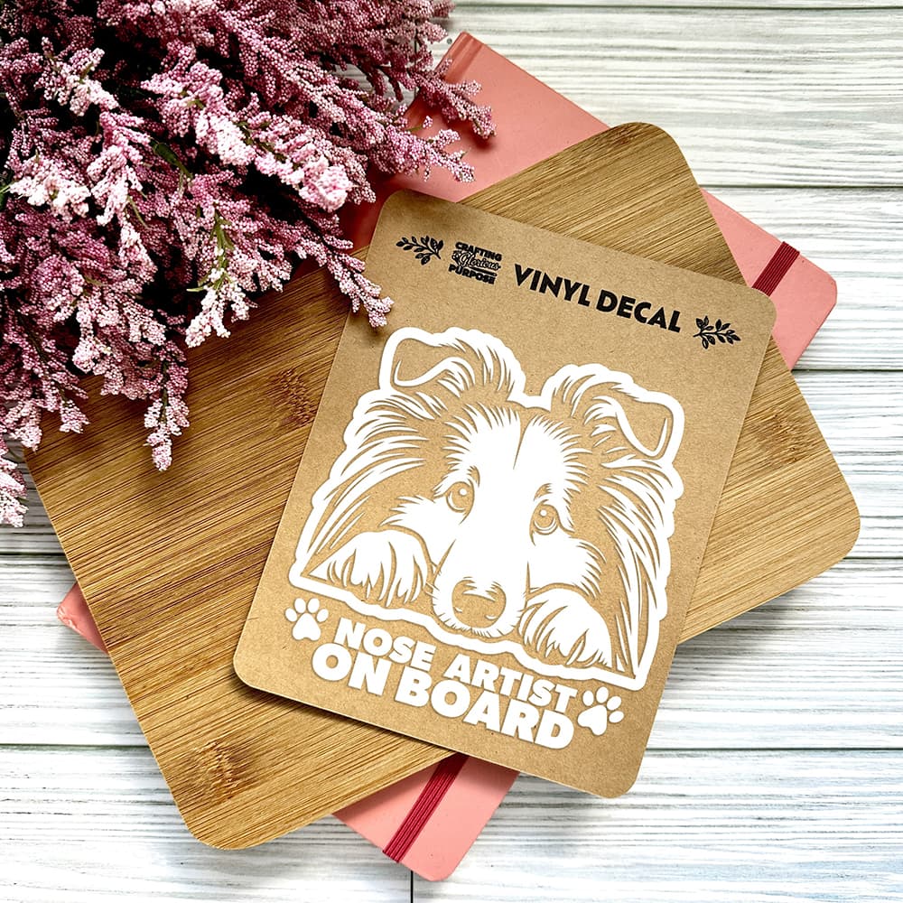Vinyl decal with a dog illustration and text on a wooden surface with pink flowers.