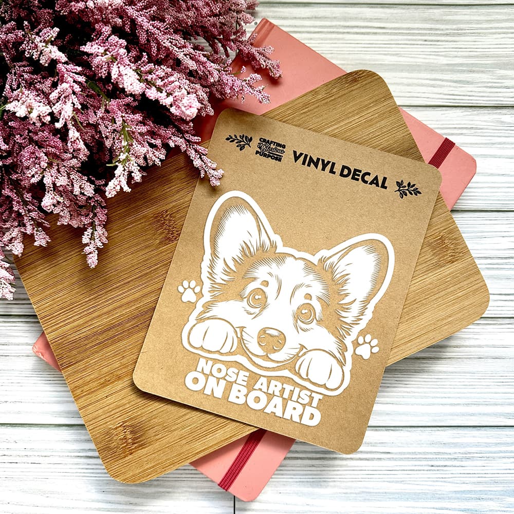 Vinyl decal with a dog illustration and text on a wooden surface with pink flowers.