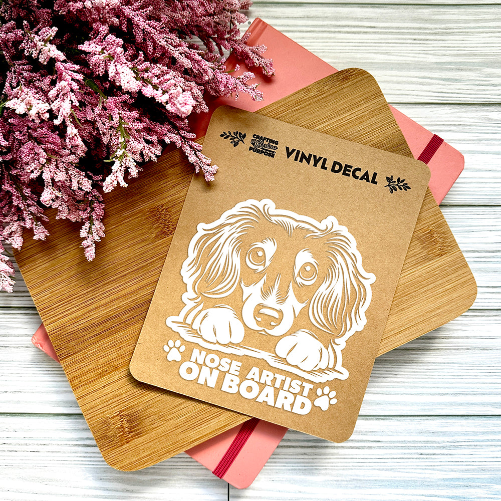 Vinyl decal with a dog illustration and text on a wooden surface with pink flowers.