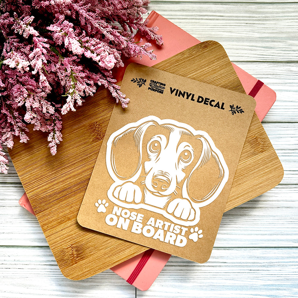 Vinyl decal with a dog illustration and text on a wooden surface with pink flowers.
