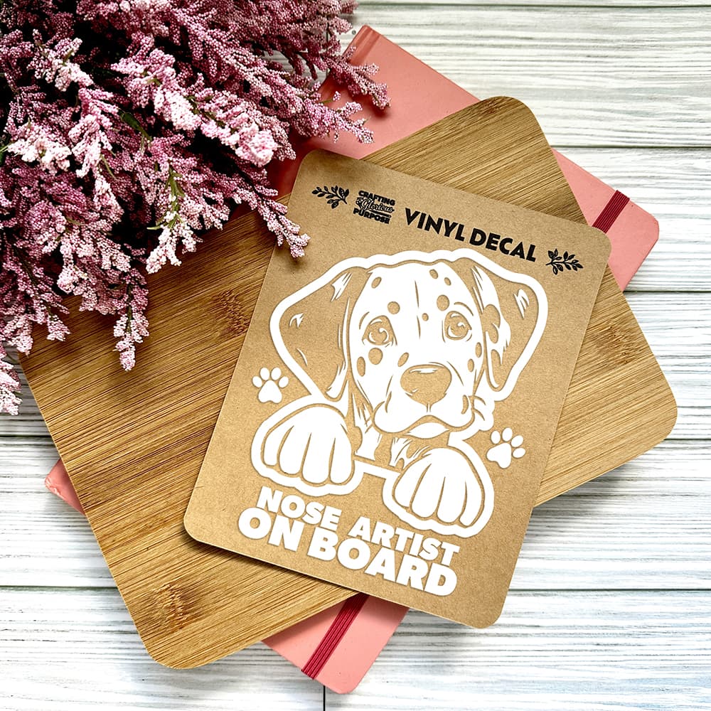 Vinyl decal with a dog illustration and text on a wooden surface with pink flowers.
